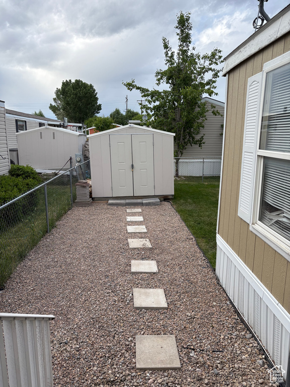 Fenced backyard featuring a shed and an outbuilding