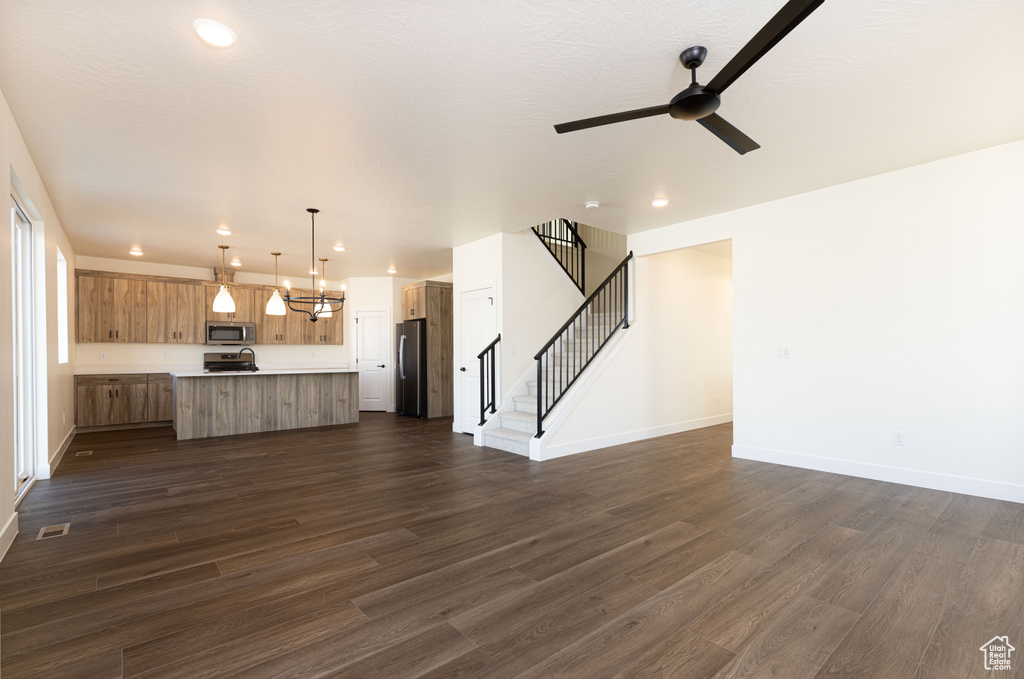 Unfurnished living room featuring a ceiling fan, dark wood finished floors, stairs, recessed lighting, and baseboards