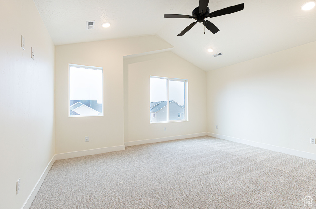 Empty room with lofted ceiling, light colored carpet, a ceiling fan, baseboards, and recessed lighting