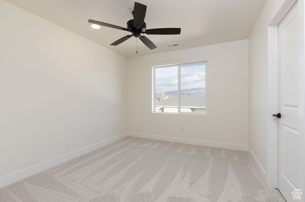 Unfurnished room with light colored carpet, baseboards, and ceiling fan
