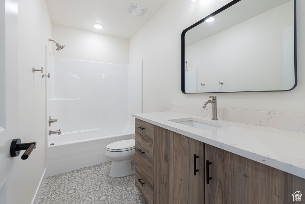 Full bath with toilet, vanity, bathtub / shower combination, and baseboards
