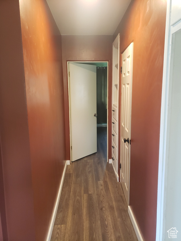 Hallway featuring dark wood finished floors and baseboards