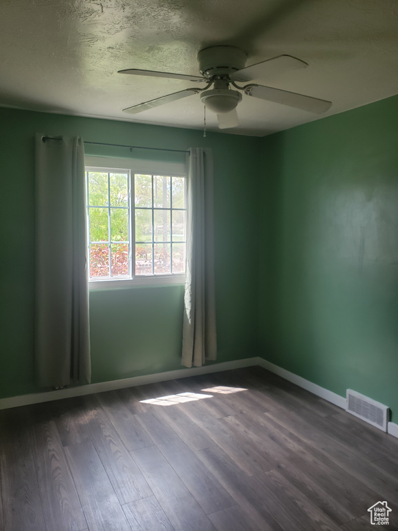 Spare room featuring ceiling fan, dark wood finished floors, baseboards, and a textured ceiling