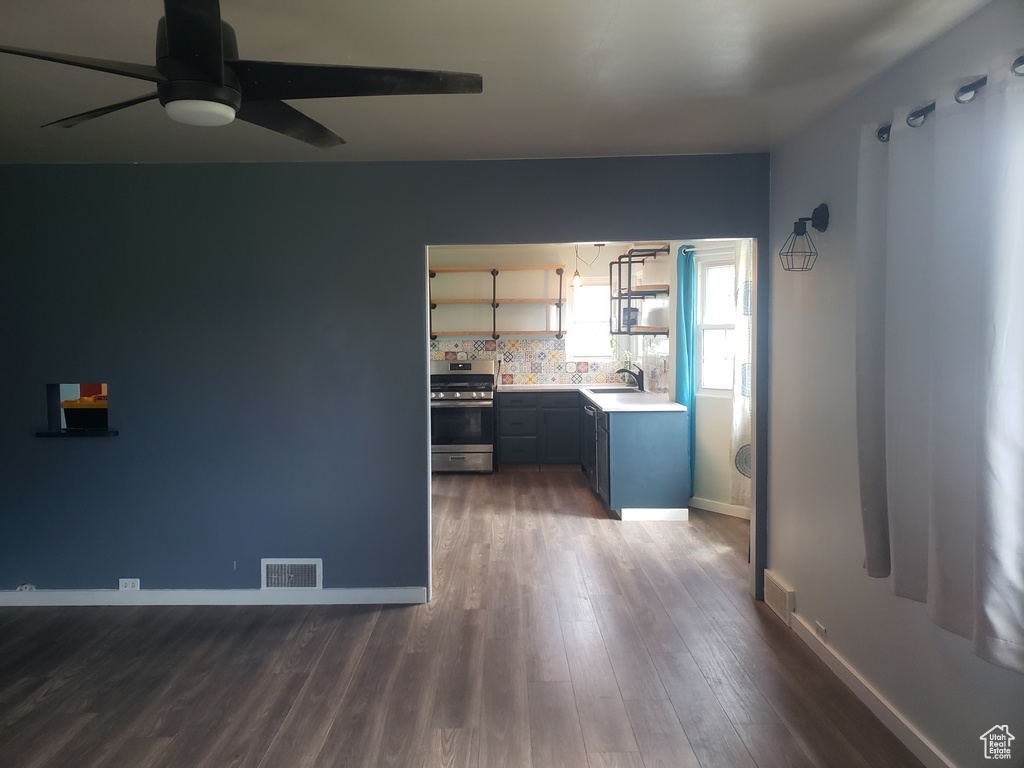 Unfurnished living room with a ceiling fan, dark wood-style floors, a sink, and baseboards