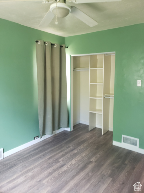 Unfurnished bedroom featuring wood finished floors, baseboards, a closet, and a ceiling fan