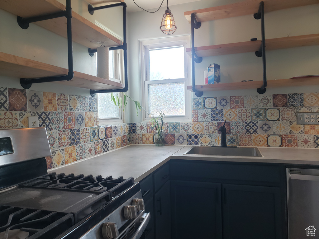 Kitchen featuring appliances with stainless steel finishes, a sink, open shelves, backsplash, and plenty of natural light