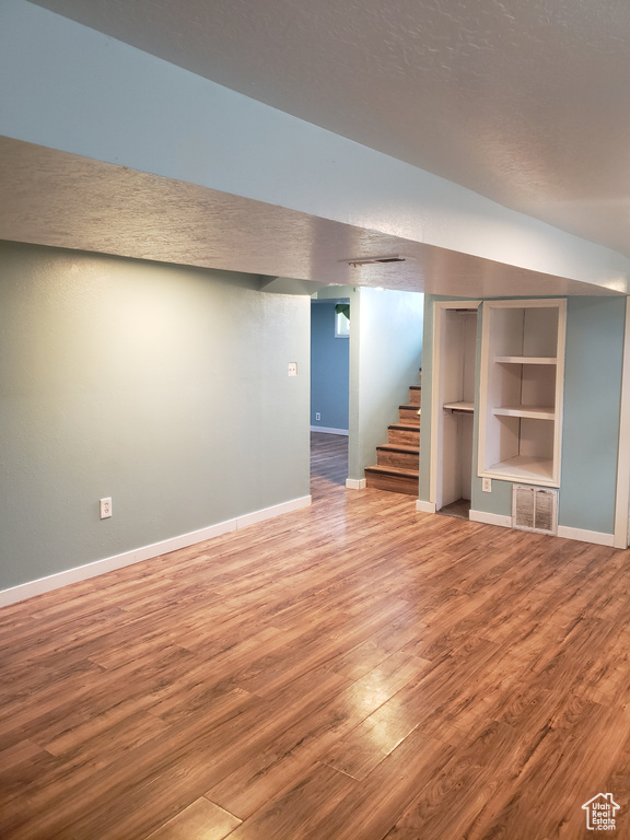 Finished below grade area with wood finished floors, baseboards, stairway, and built in features