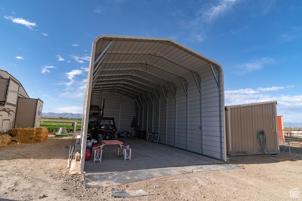 View of parking with a detached carport, a mountain view, and dirt driveway