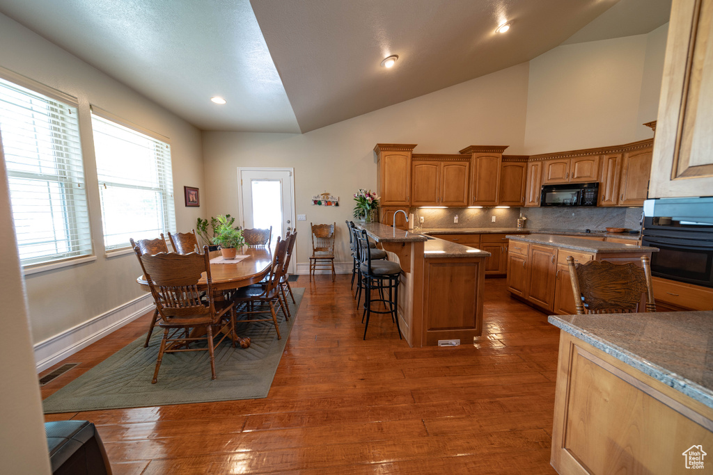 Dining area featuring wood finished floors, baseboards, lofted ceiling, and recessed lighting