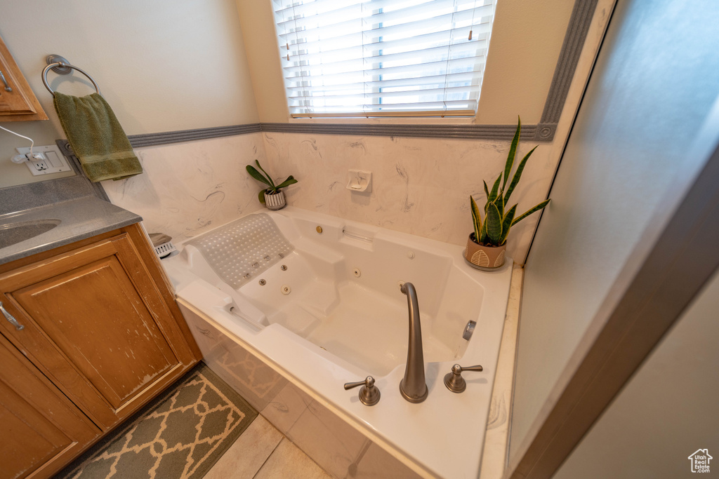 Bathroom featuring a tub with jets, vanity, and tile patterned floors