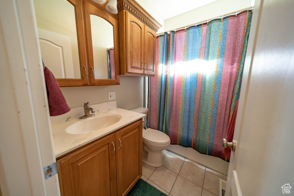 Bathroom with tile patterned floors, toilet, vanity, and shower / tub combo