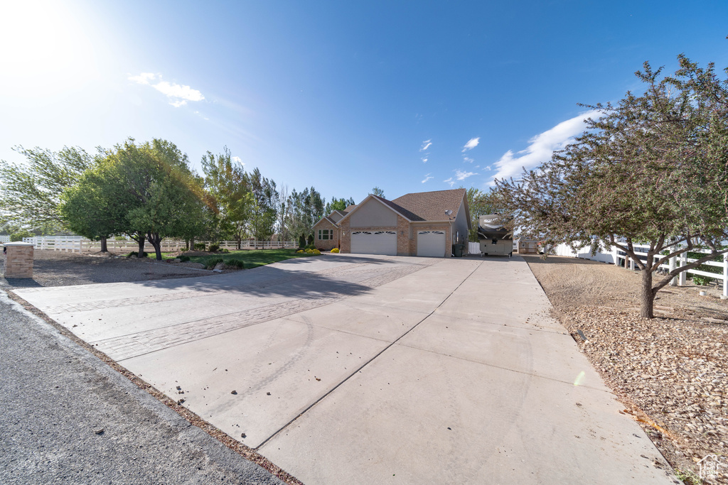 View of front of property with concrete driveway, a garage, and fence