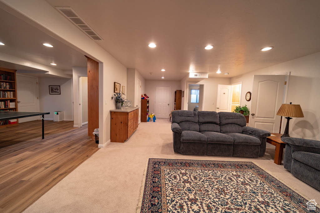 Living area featuring recessed lighting, light carpet, baseboards, and light wood-type flooring