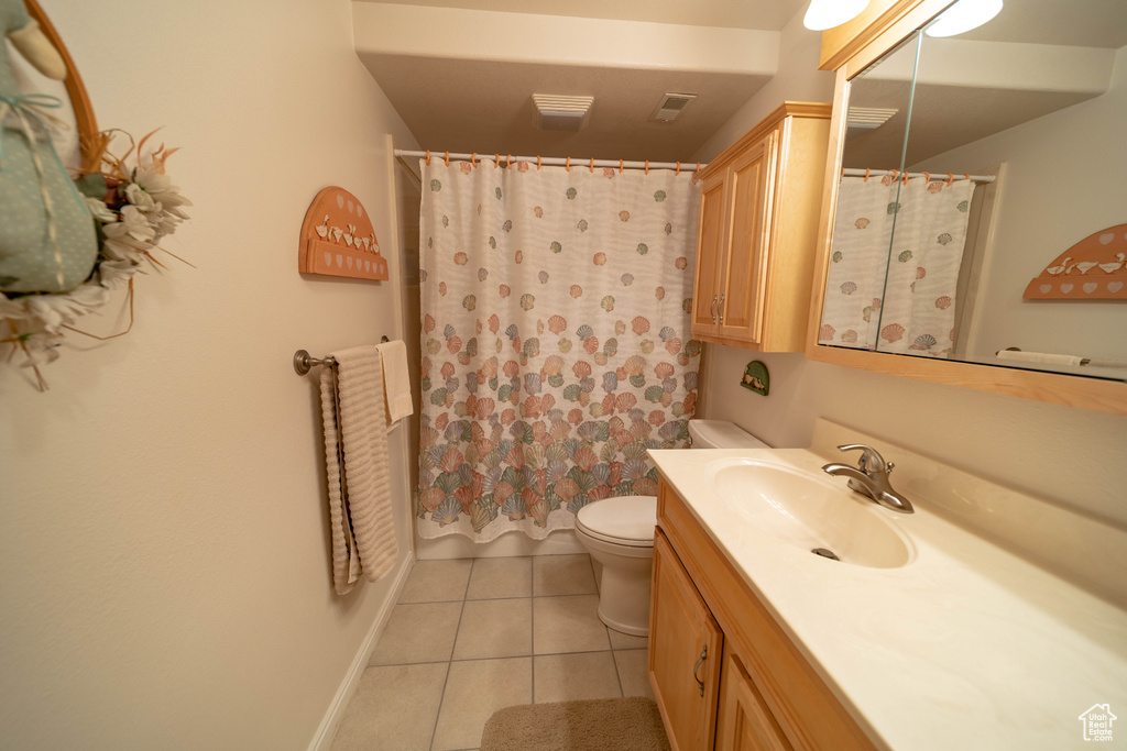 Full bath featuring tile patterned floors, toilet, vanity, and baseboards