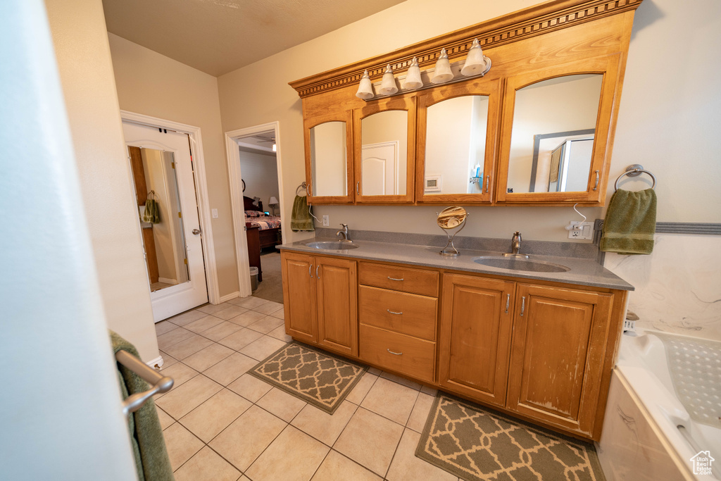 Bathroom featuring tile patterned floors, double vanity, and a bath