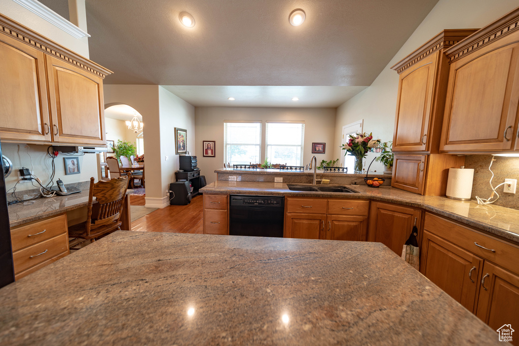 Kitchen with dishwasher, a sink, wood finished floors, backsplash, and arched walkways