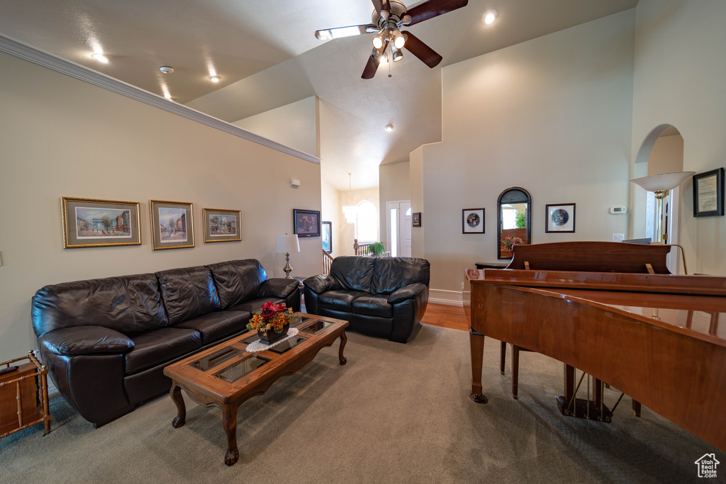 Carpeted living area featuring ceiling fan and high vaulted ceiling