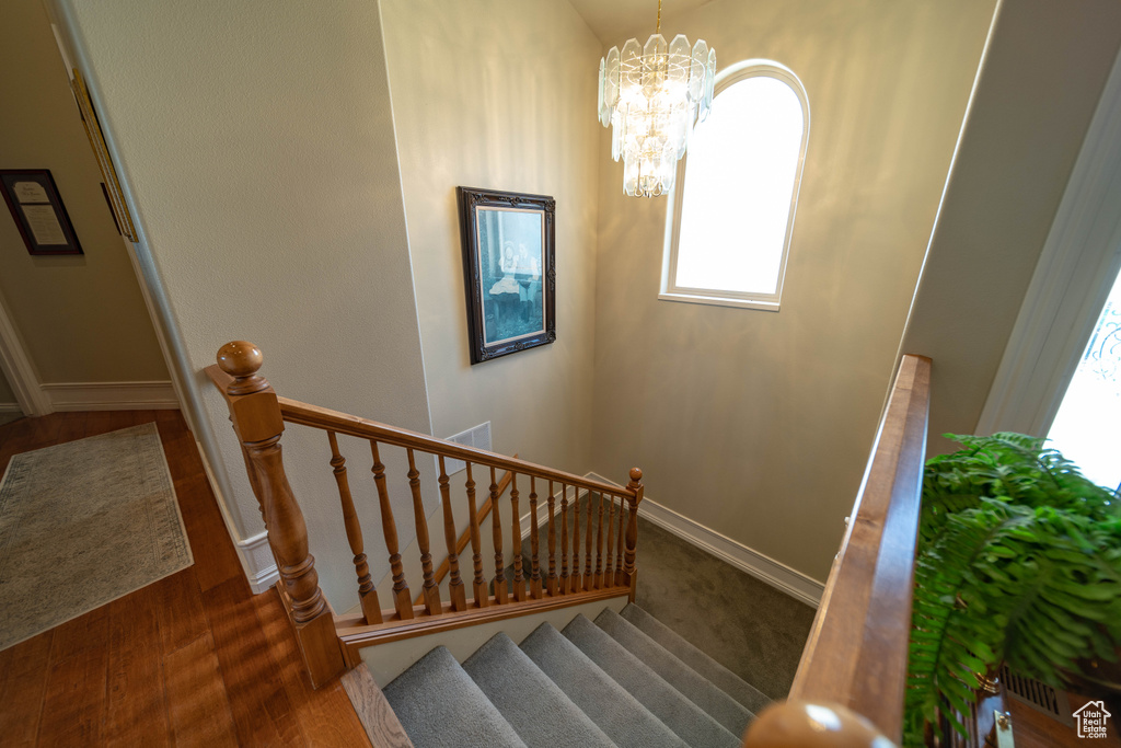 Stairway with plenty of natural light, baseboards, and a chandelier