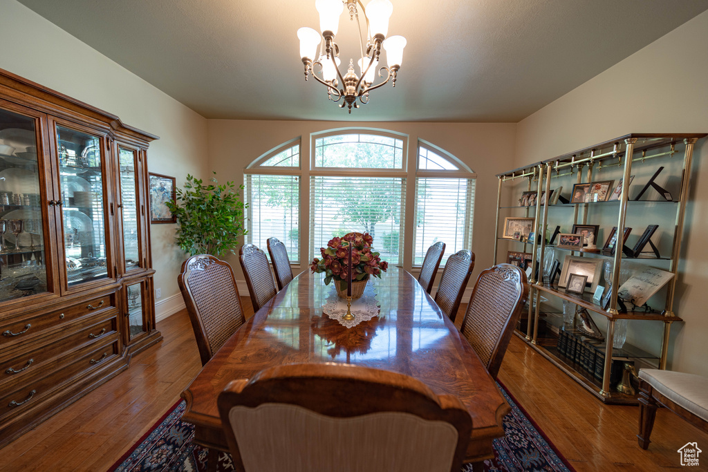 Dining area with a chandelier, plenty of natural light, wood finished floors, and baseboards