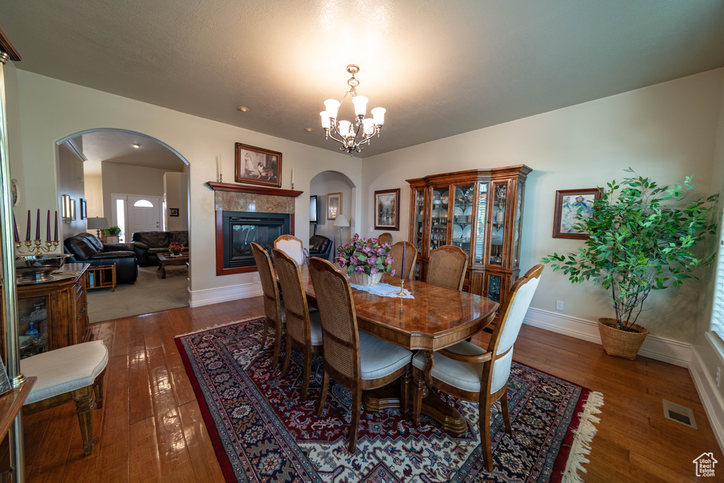 Dining room with arched walkways, hardwood / wood-style floors, baseboards, and a chandelier