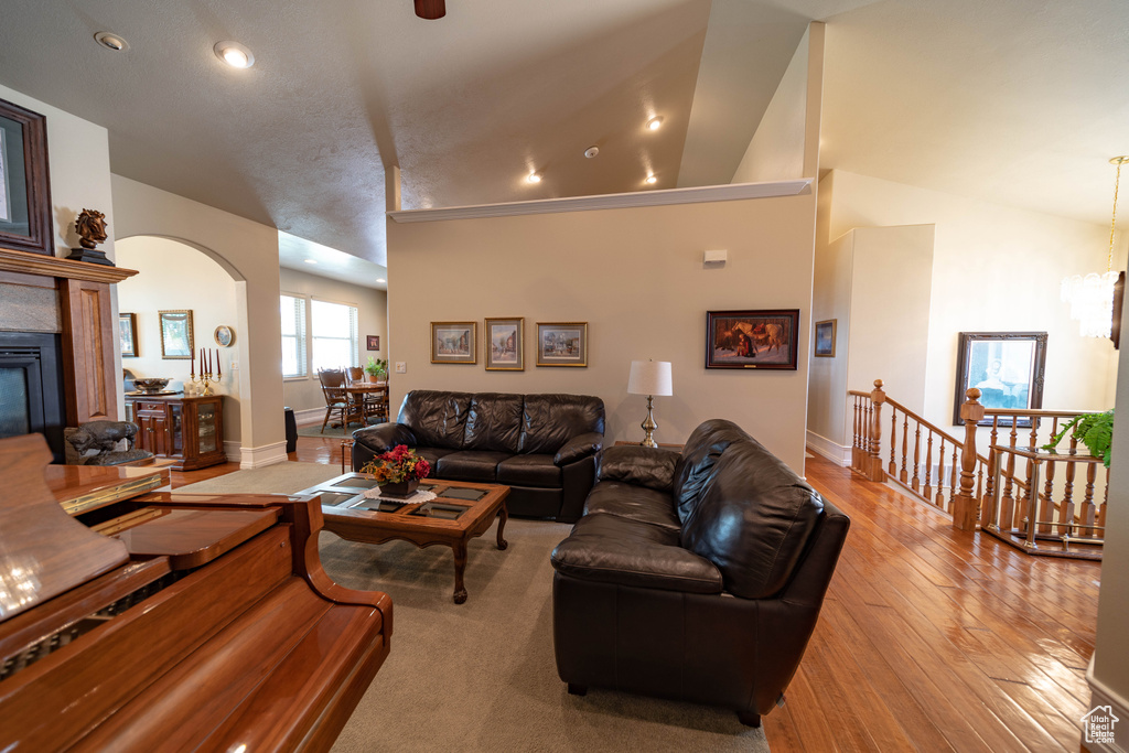 Living area with arched walkways, a glass covered fireplace, hardwood / wood-style flooring, baseboards, and recessed lighting