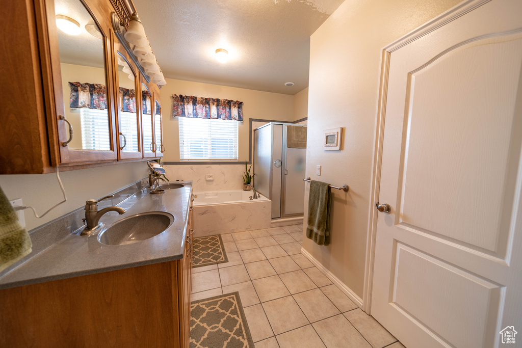 Full bath featuring tile patterned flooring, a stall shower, a bath, double vanity, and baseboards