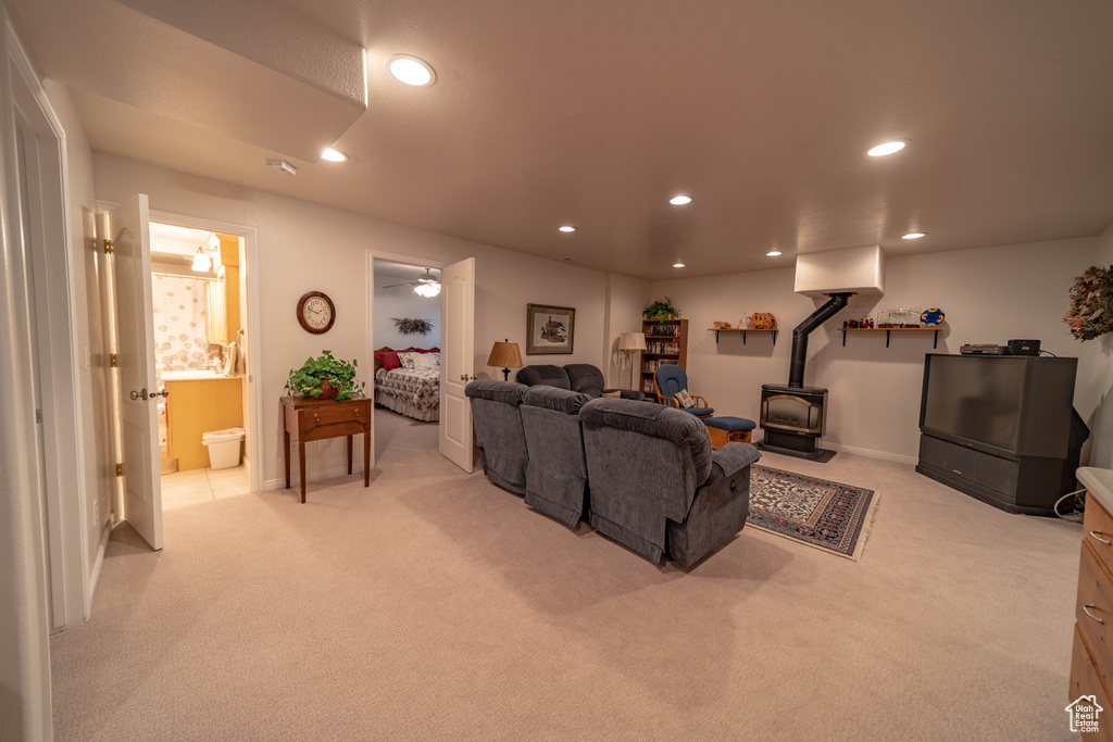 Living room with a wood stove, light carpet, recessed lighting, and baseboards