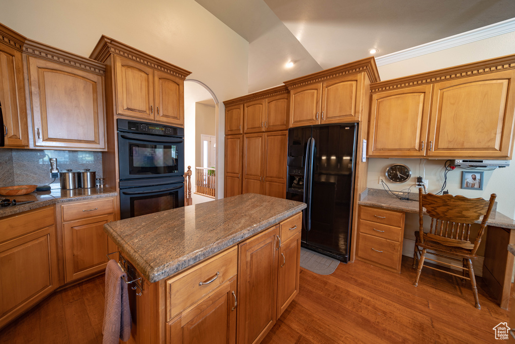 Kitchen featuring black appliances, dark wood finished floors, decorative backsplash, brown cabinetry, and recessed lighting