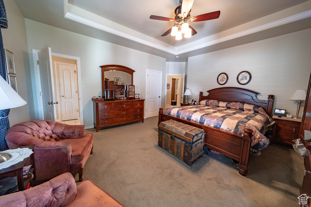 Bedroom with carpet, a raised ceiling, and a ceiling fan