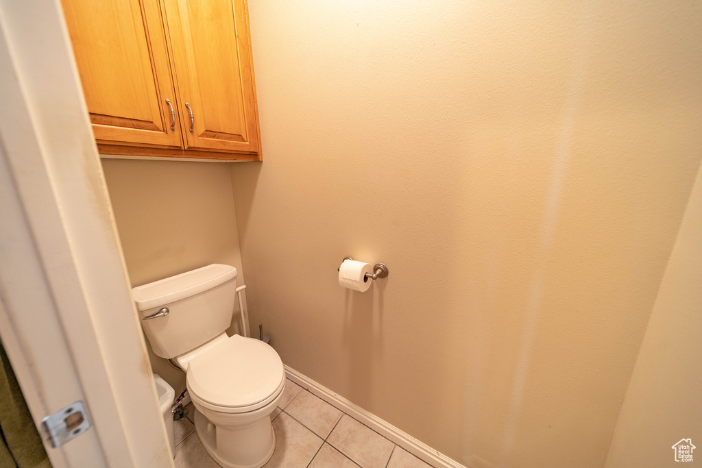 Bathroom featuring tile patterned floors, toilet, and baseboards
