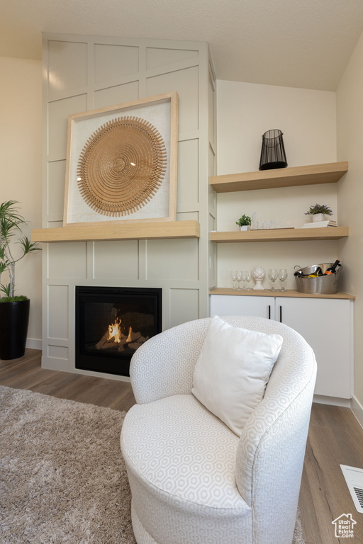 Living area featuring wood finished floors, a glass covered fireplace, and baseboards