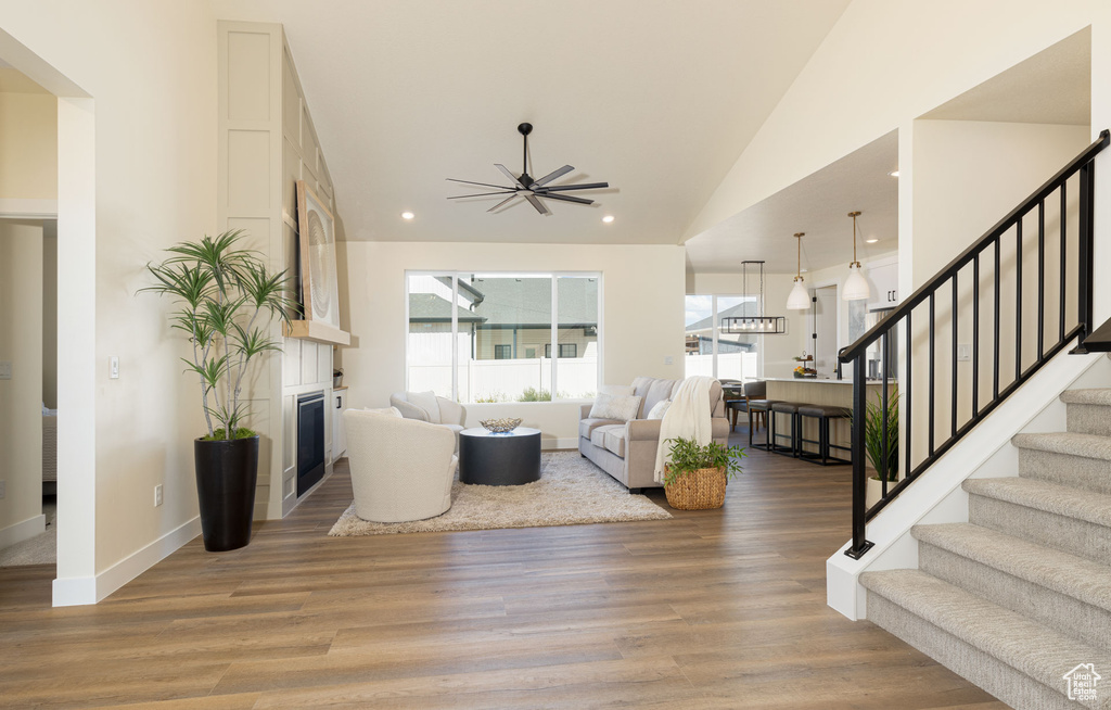 Living area featuring stairs, a glass covered fireplace, a ceiling fan, wood finished floors, and recessed lighting