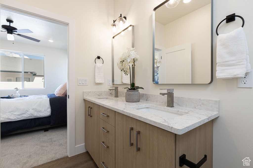 Ensuite bathroom with wood finished floors, a ceiling fan, and double vanity