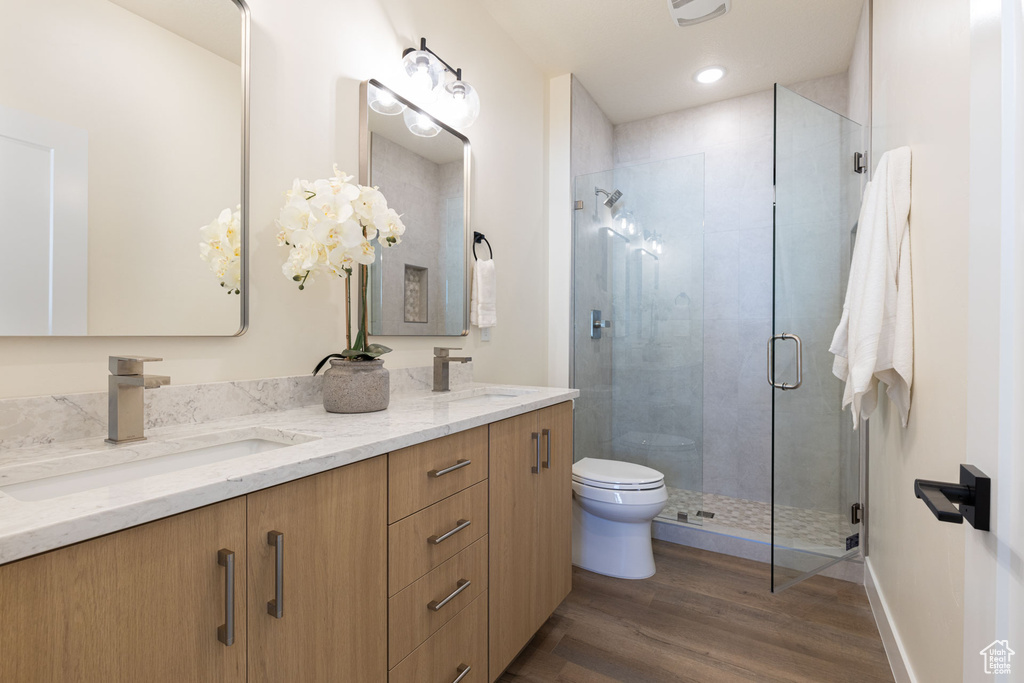 Full bath featuring wood finished floors, a stall shower, toilet, and double vanity