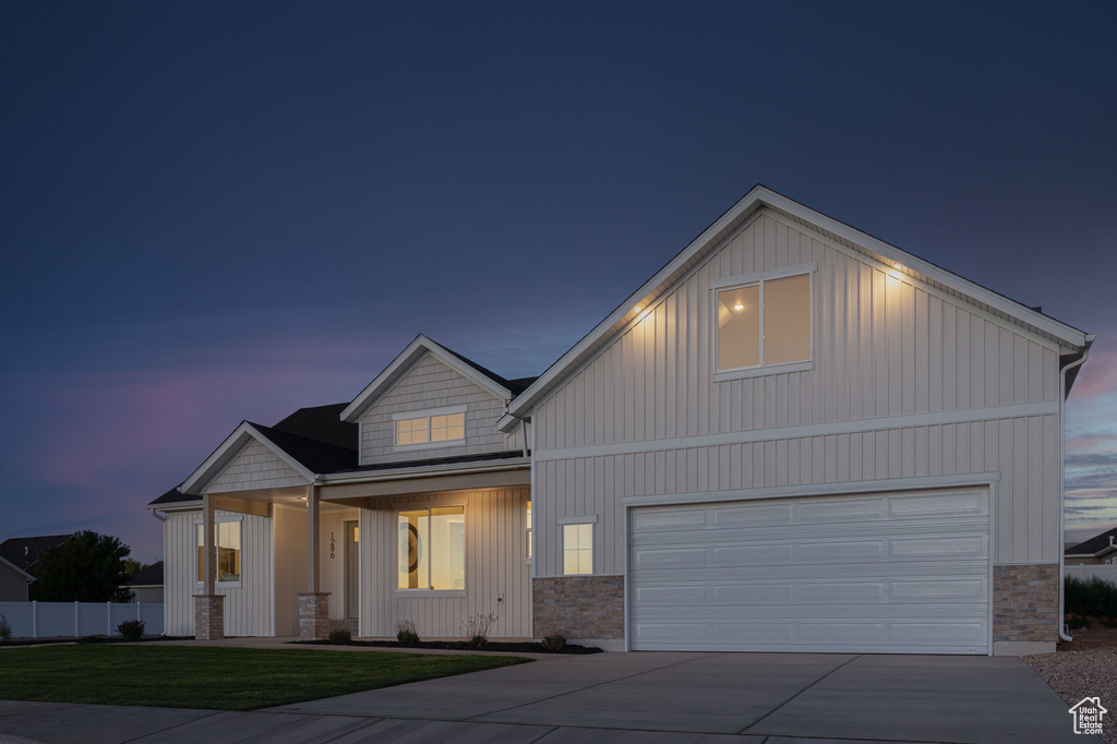Modern inspired farmhouse featuring concrete driveway, stone siding, a porch, an attached garage, and board and batten siding