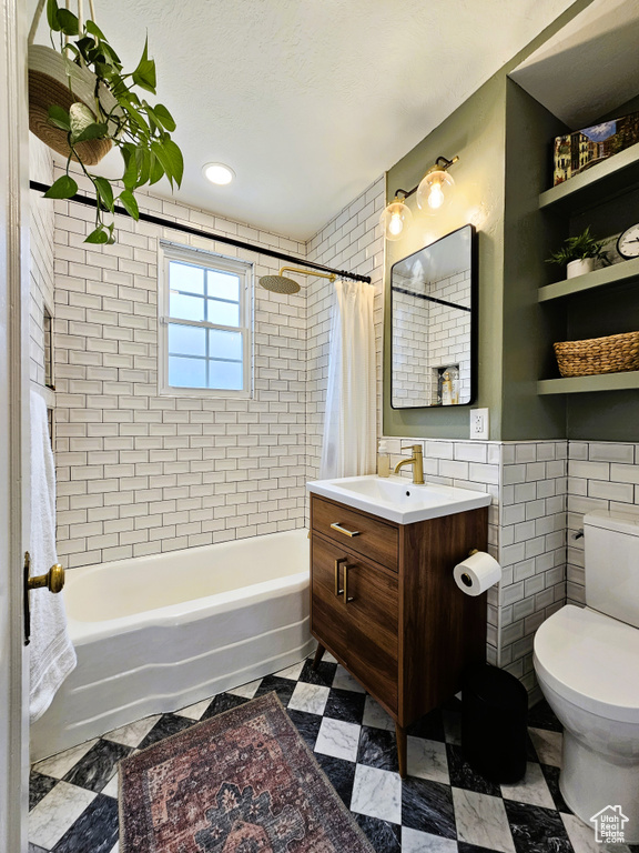 Bathroom with tile walls, shower / bathtub combination with curtain, toilet, vanity, and tile patterned floors