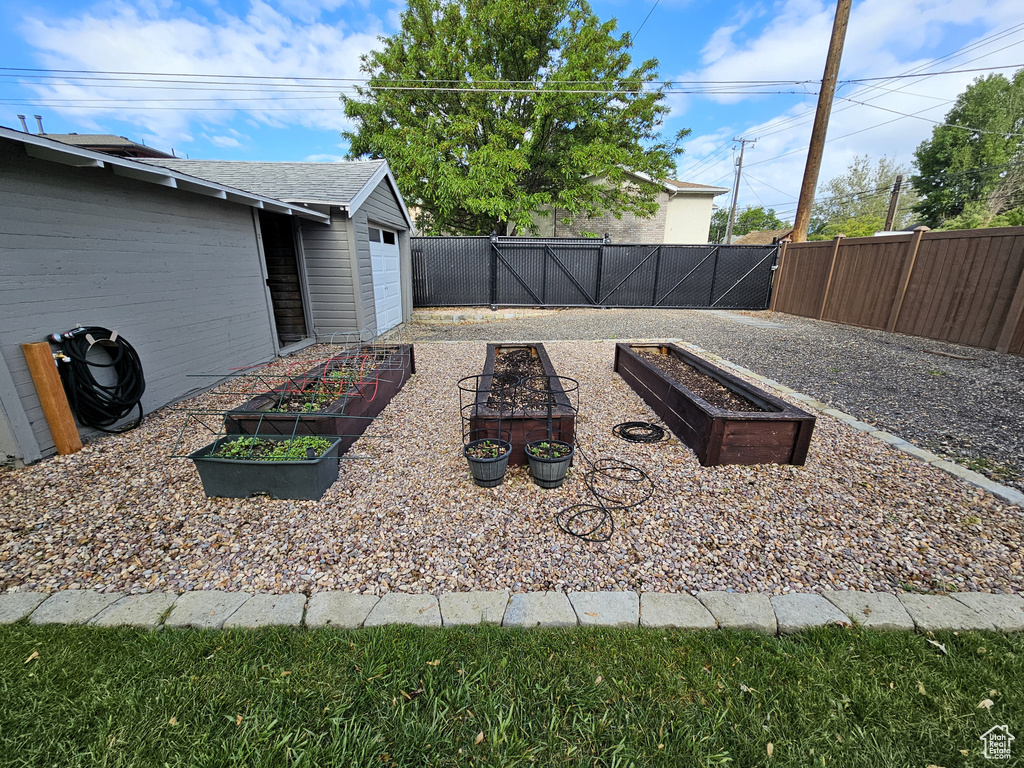 Fenced backyard featuring a vegetable garden and a garage