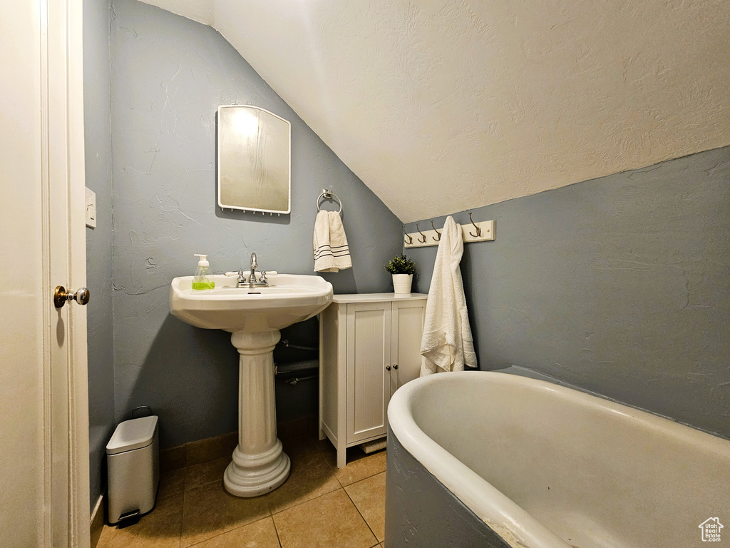 Bathroom with vaulted ceiling, a soaking tub, and tile patterned flooring