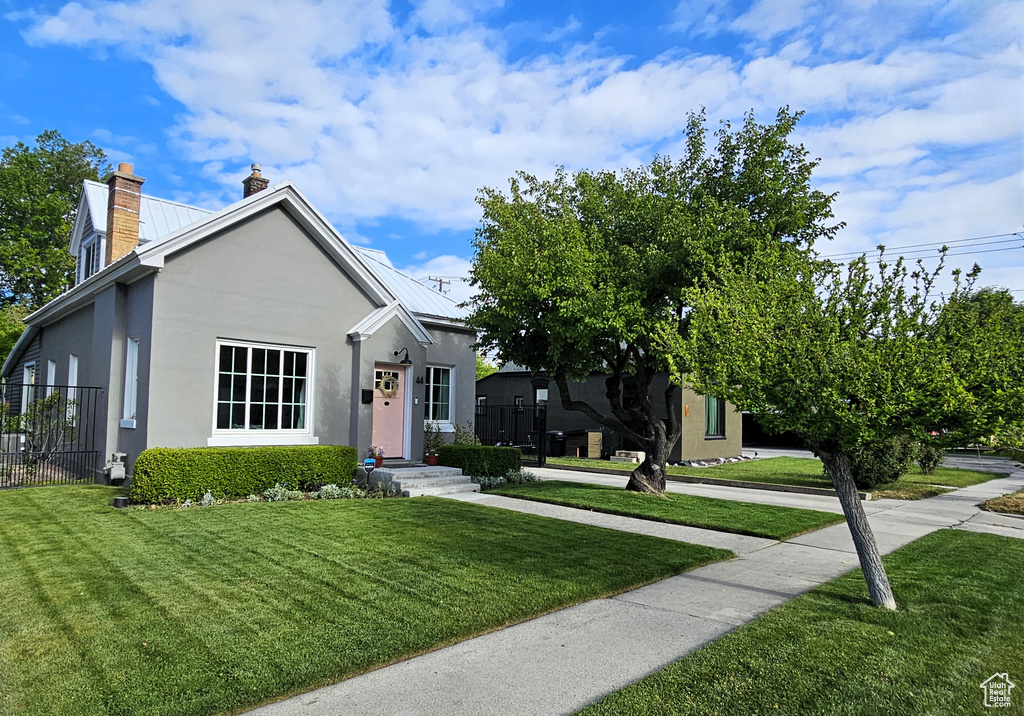 View of front of property featuring stucco siding, a chimney, and metal roof