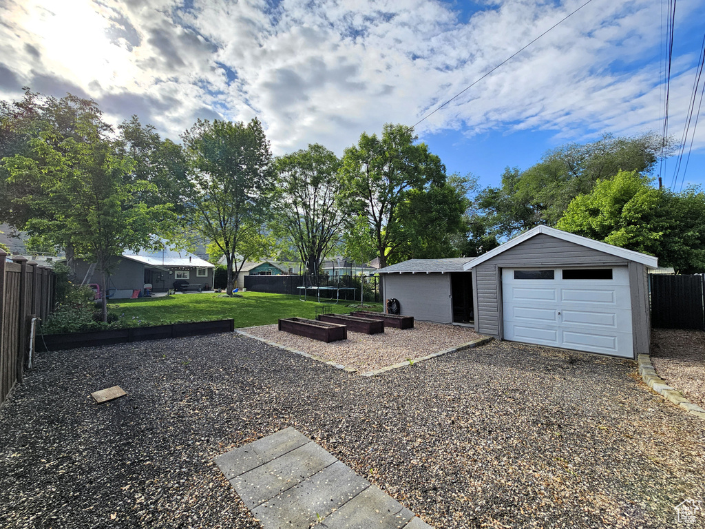 View of yard featuring an outdoor structure, a vegetable garden, a garage, and driveway