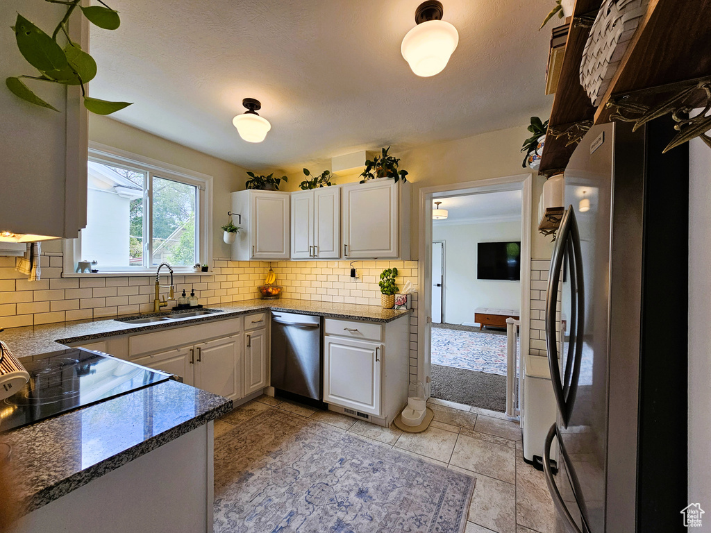 Kitchen featuring a sink, stainless steel appliances, backsplash, and white cabinetry