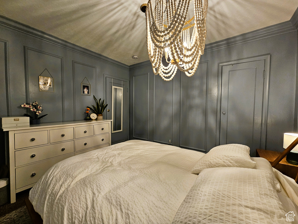 Bedroom with a decorative wall, crown molding, and a chandelier