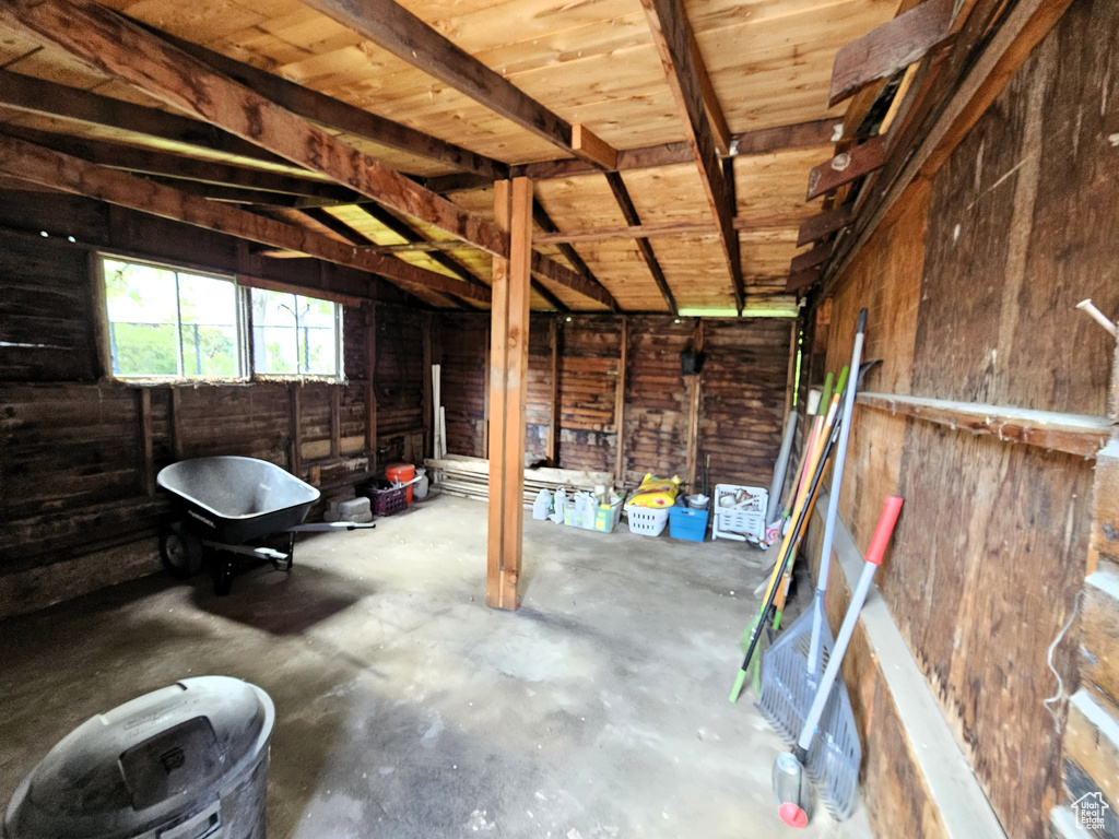 Misc room featuring unfinished concrete floors, vaulted ceiling, and wood walls