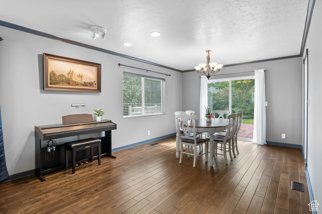 Dining space with crown molding, a chandelier, baseboards, plenty of natural light, and a textured ceiling