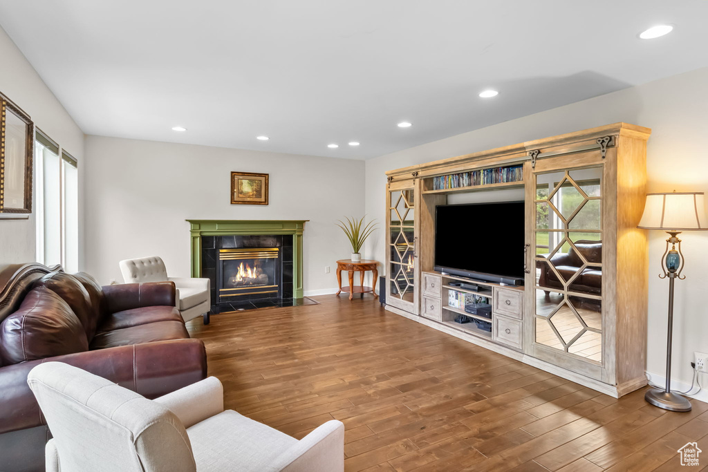 Living area with wood finished floors, recessed lighting, baseboards, a fireplace, and healthy amount of natural light