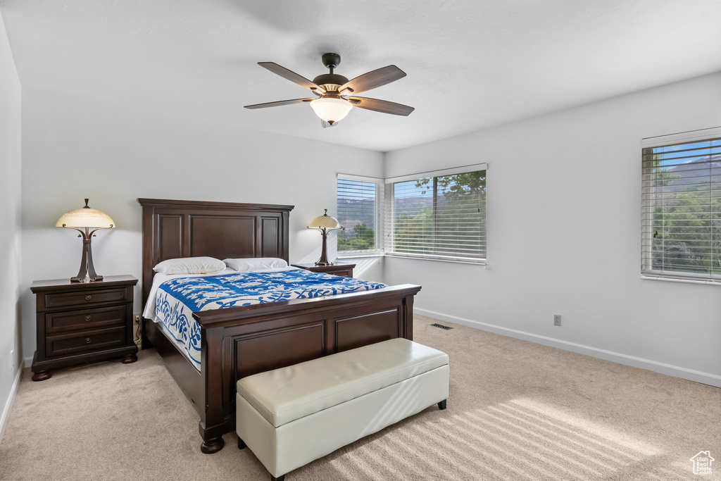Bedroom featuring light carpet, baseboards, and ceiling fan