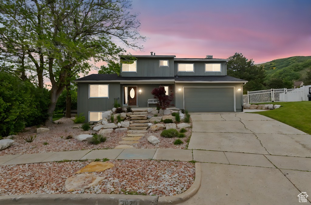Traditional home with fence, driveway, a garage, and covered porch
