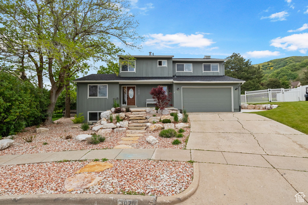 Traditional-style home featuring fence, driveway, an attached garage, covered porch, and a mountain view