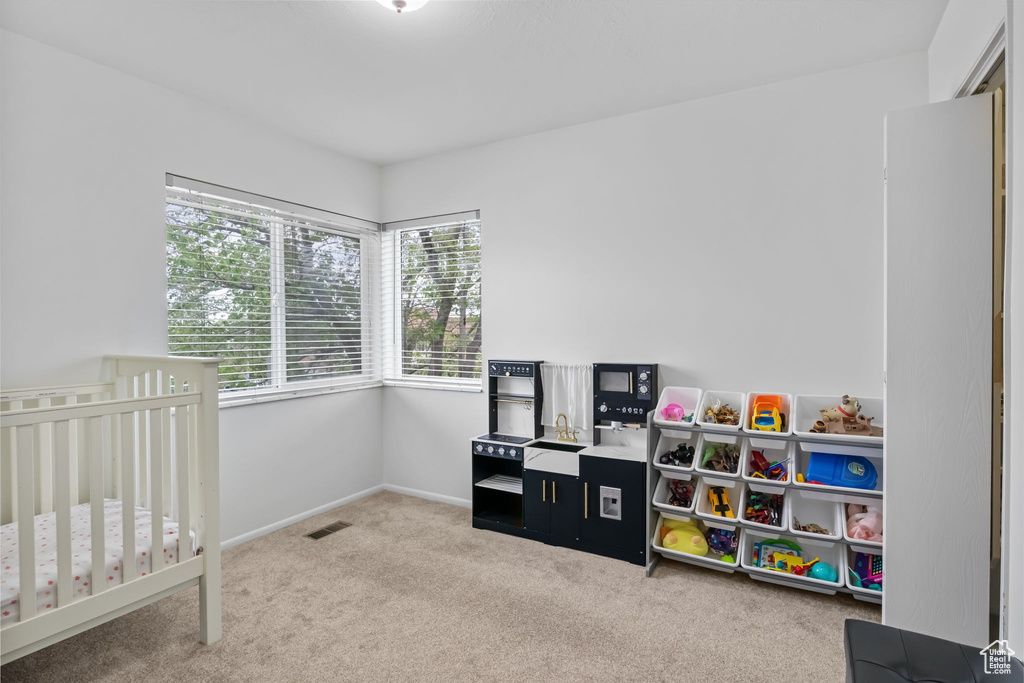 Carpeted bedroom with a nursery area and baseboards