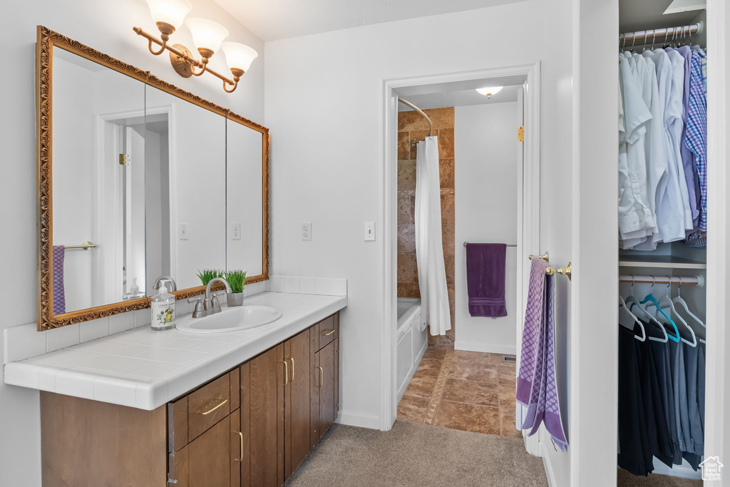 Bathroom with vanity, a chandelier, shower / bath combo with shower curtain, and a spacious closet